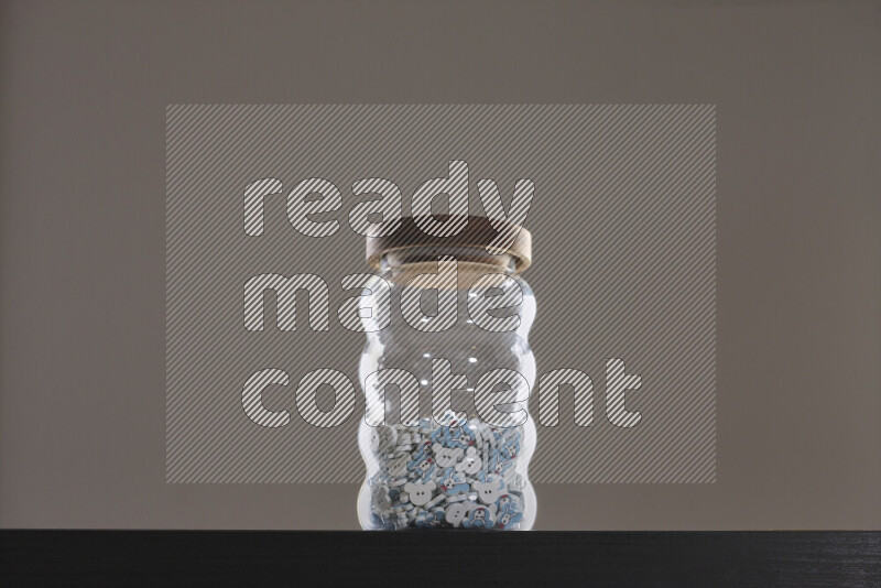 أزرار متنوعة في وعاء زجاجي علي خلفية سوداء