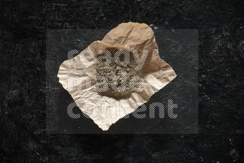 بودرة الهيل في قطعة من الورق على خلفية سوداء