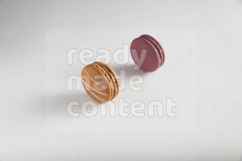45º Shot of of two assorted Brown Irish Cream, and Red Cherry macarons on white background