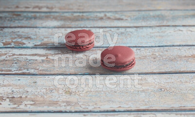 45º Shot of two Red Cherry macarons on light blue wooden background