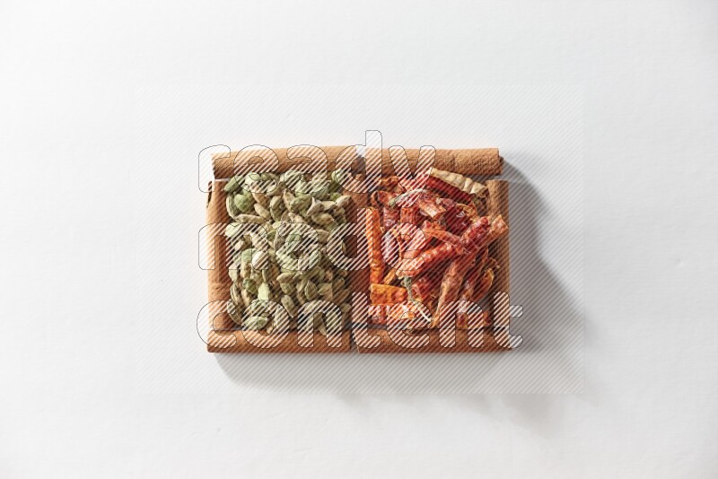 2 squares of cinnamon sticks full of cardamom and dried red chilis on white flooring