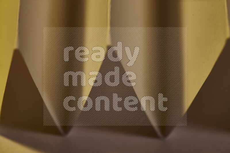 صورة مجردة مقربة تظهر طيات ورقية هندسية حادة بتدرجات الوان دافئة