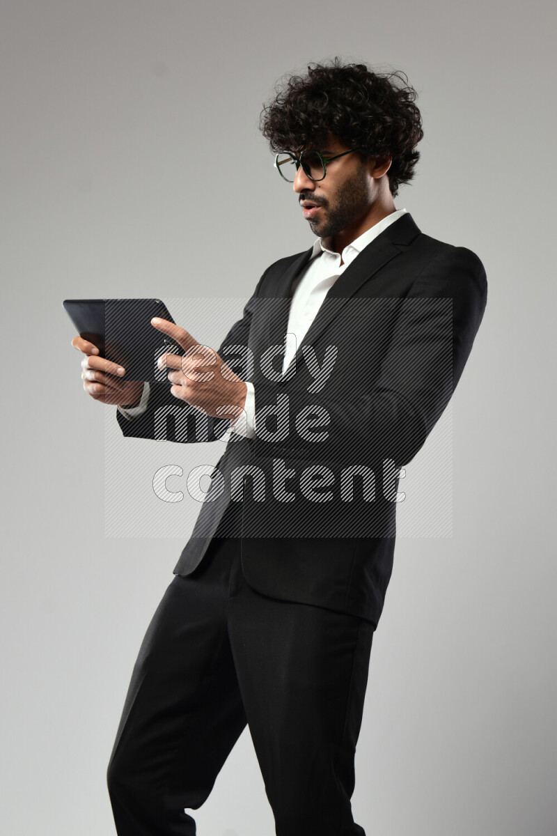 A man wearing formal standing and gaming on a tablet on white background