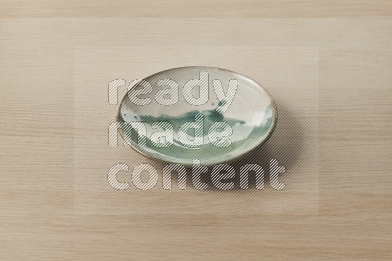 A multicolored pottery plate on light wooden background