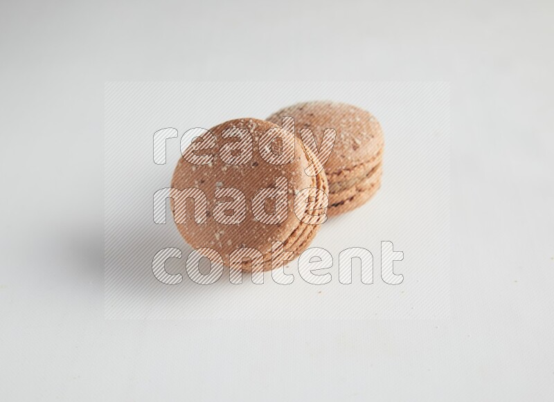 45º Shot of two Brown Hazelnuts macarons on white background