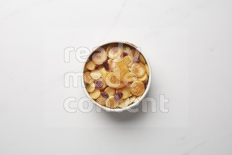 Top-view shot of orange candy cereal pancakes in a round bowl on white background