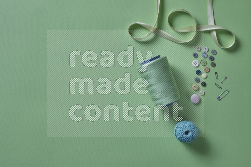 A green collection of sewing and tailoring tools arranged on a green background