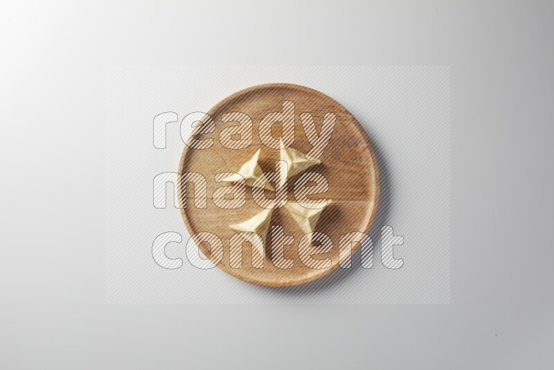Four Sambosas on a wooden round plate on a white background