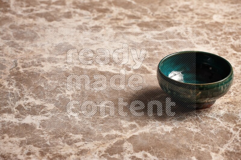A dark green pottery bowl on beige marble background