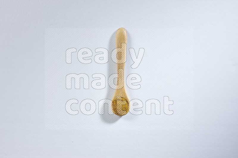 ملعقة خشبية ممتلئة ببودرة الكركم على خلفية بيضاء