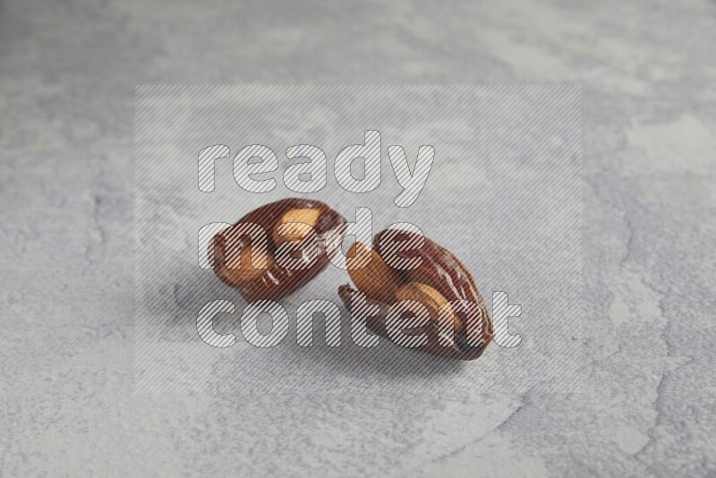 Two Almond stuffed date on a light grey background