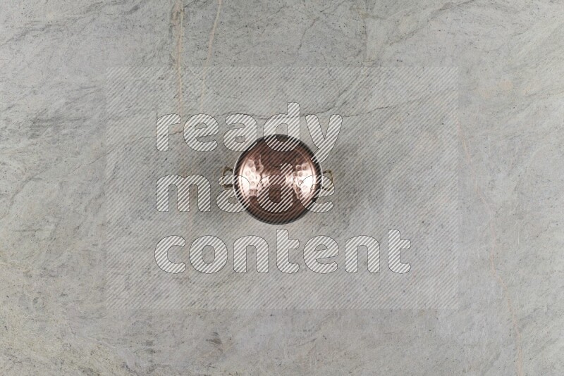 A small copper pot on grey marble background