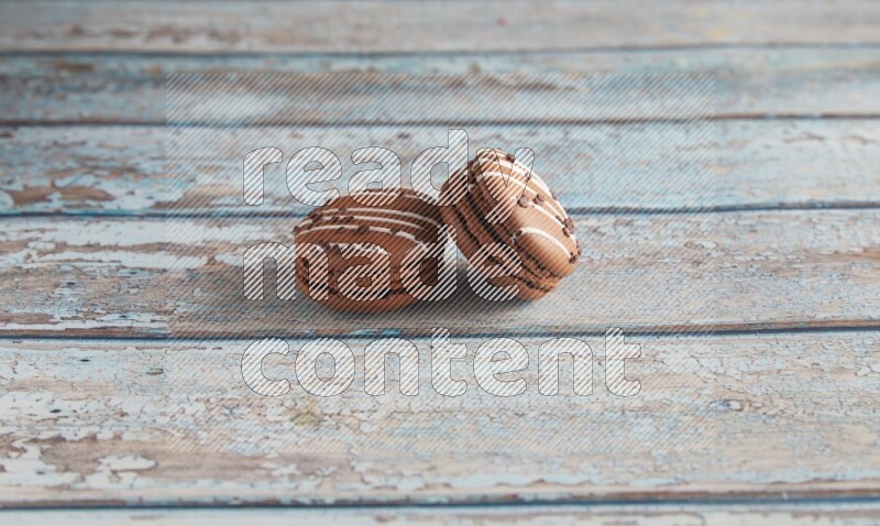 45º Shot of two Brown white  Chocolate Caramel macarons on light blue wooden background