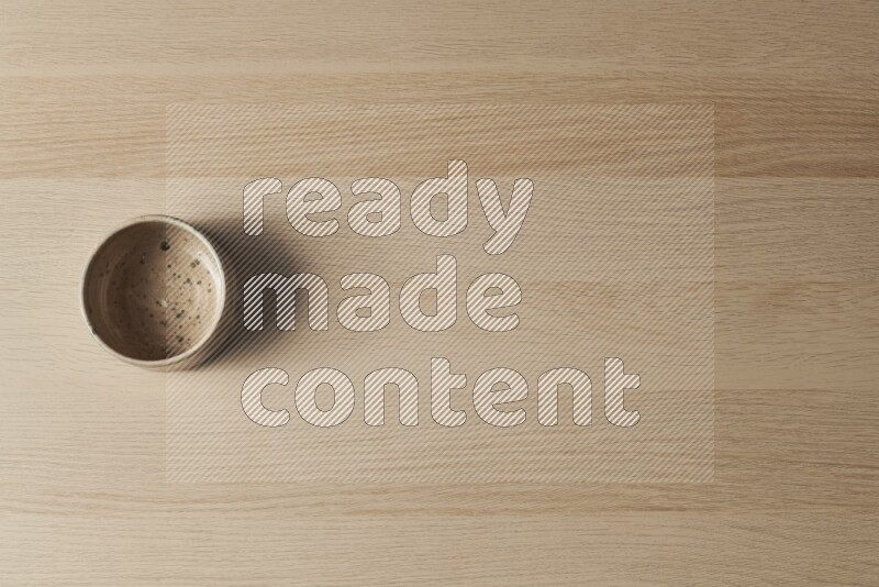 A multicolored pottery bowl on light wooden background