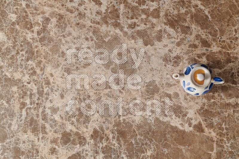 A pottery teapot on beige marble background
