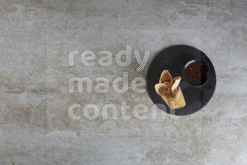 wonton cups with soy sauce ramkin on circle slate on grey textured counter top