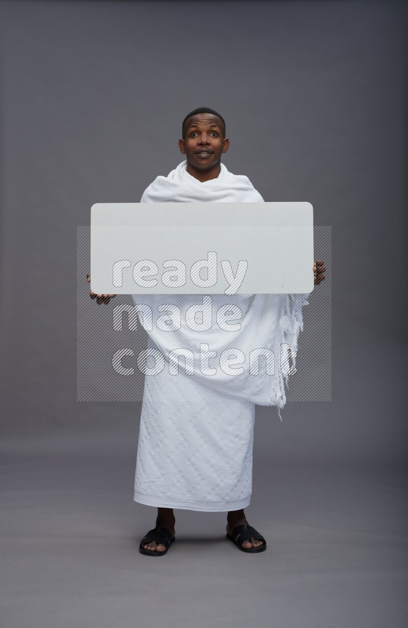 A man wearing Ehram Standing holding board sign on gray background
