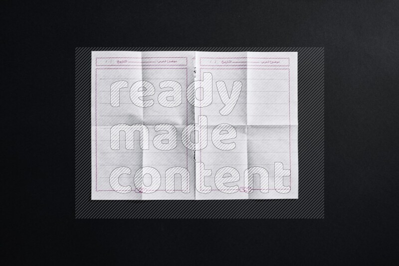 Folded notebook sheet on black background