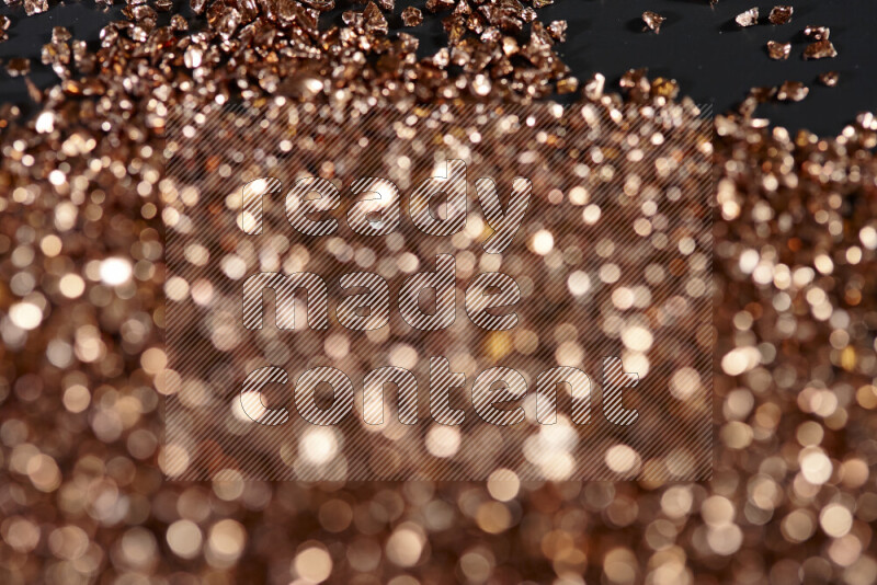Bronze shimmering fragments of glass scattered on a black background