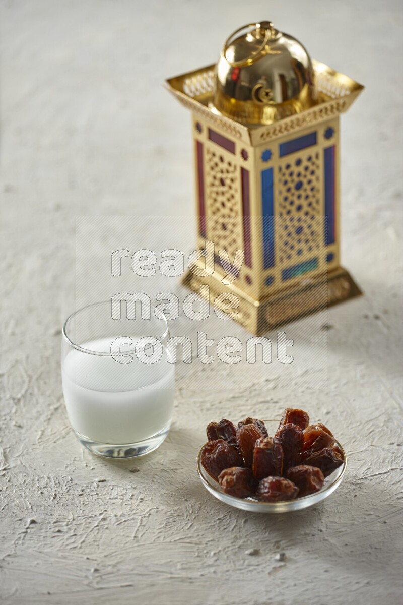 A golden lantern with different drinks, dates, nuts, prayer beads and quran on textured white background
