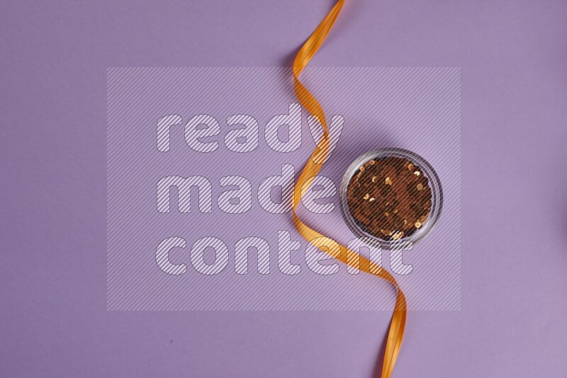 An orange collection of sewing and tailoring tools arranged on a purple background