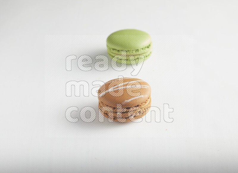 45º Shot of of two assorted Brown Irish Cream, and Green Pistachio macarons on white background