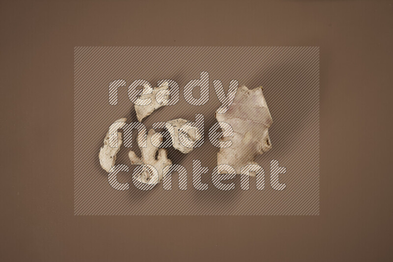 بهارات كاملة متنوعة تتضمن زنجبيل طازج ومجفف، أعواد قرفة، هيل، أصابع كركم، قرنفل، يانسون نجمي على خلفية بيج