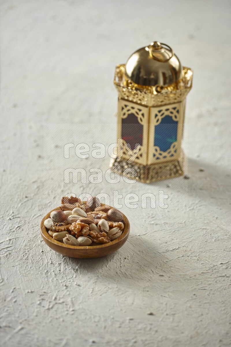 A golden lantern with different drinks, dates, nuts, prayer beads and quran on textured white background