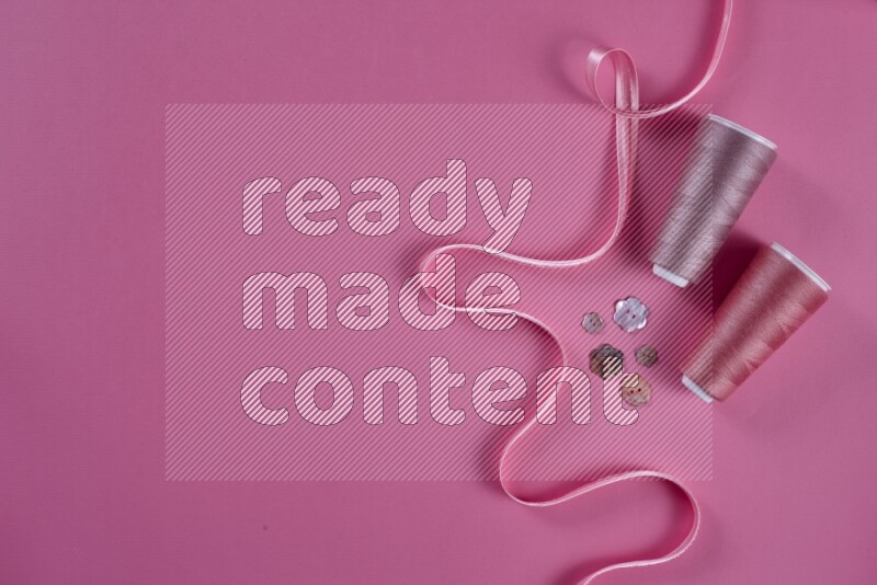 A pink collection of sewing and tailoring tools arranged on a pink background