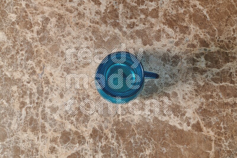 A colored glass jug on beige marble background