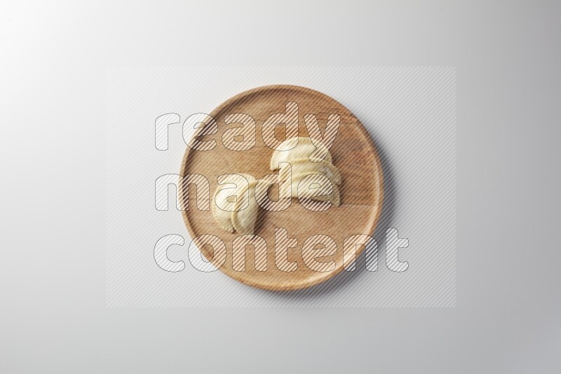 Five Sambosas on a wooden round plate on a white background