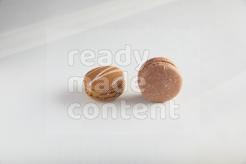 45º Shot of of two assorted Brown Irish Cream, and Brown Hazelnuts macarons on white background