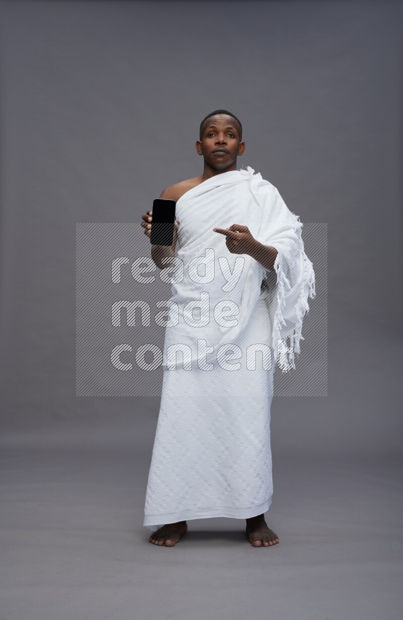 A man wearing Ehram Standing showing phone to camera on gray background