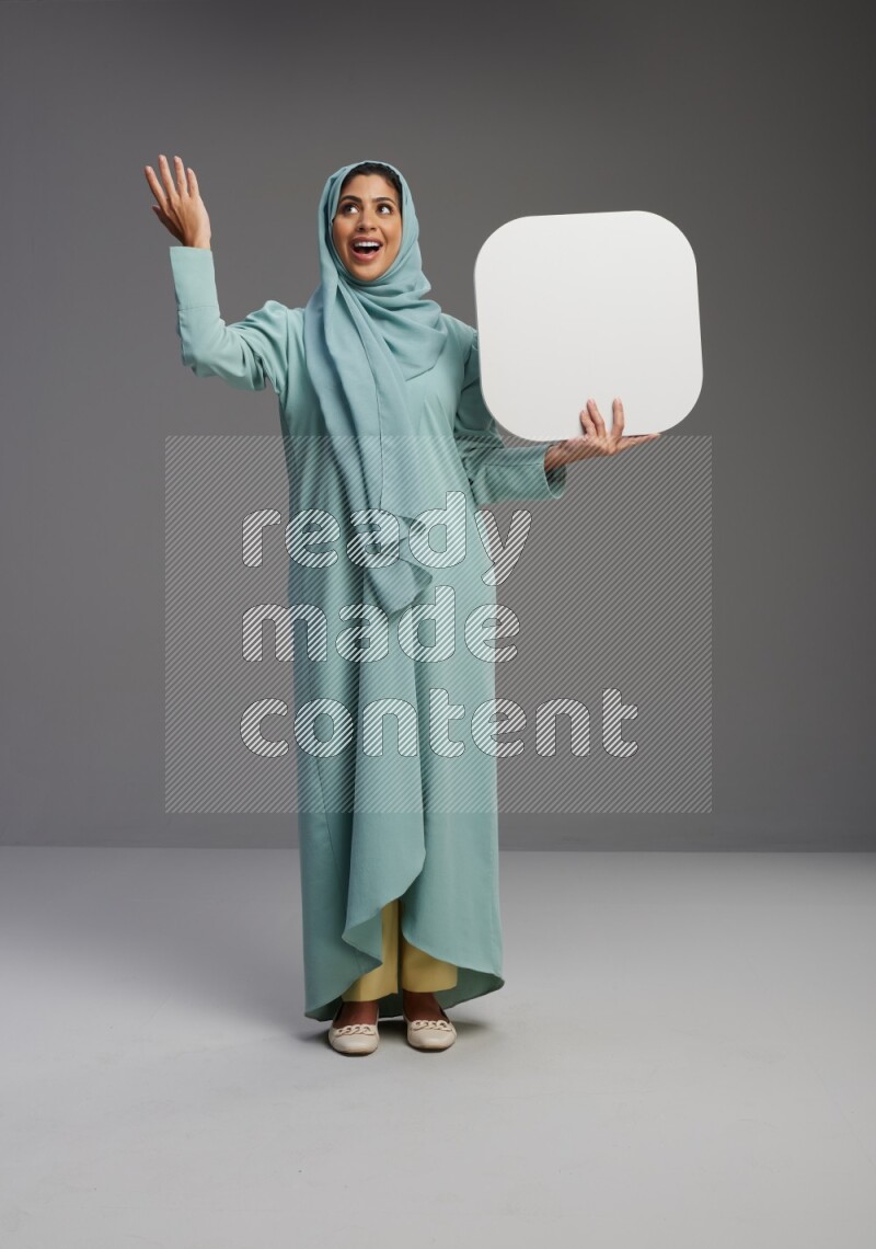 Saudi Woman wearing Abaya standing holding social media sign on Gray background