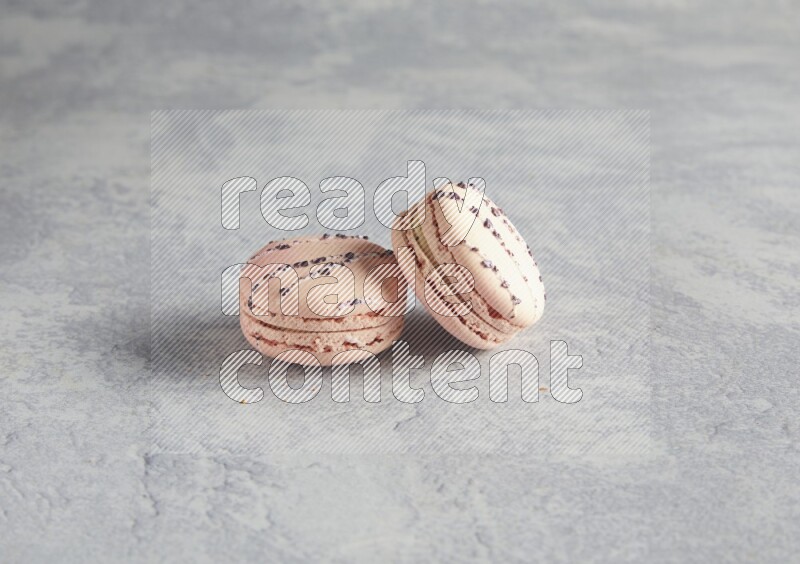 45º Shot of two pink orange blossom macarons  on white  marble background