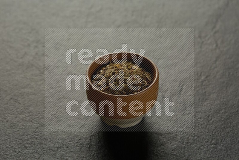 multi color round sauce bowl filled with herbs on grey textured countertop