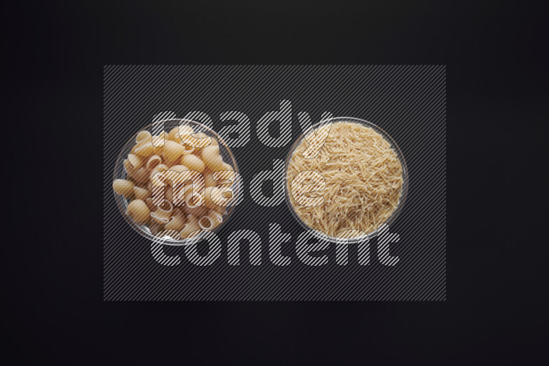 Different pasta types in glass bowls on black background