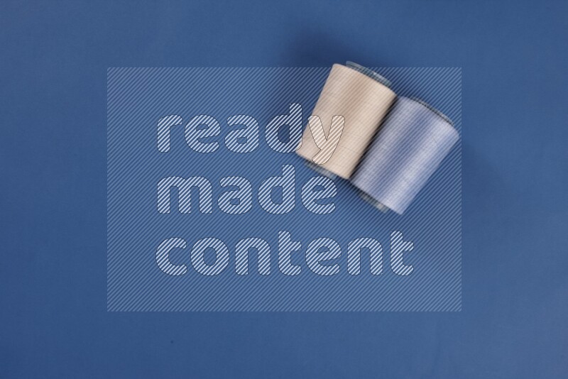 A white collection of sewing and tailoring tools arranged on a blue background