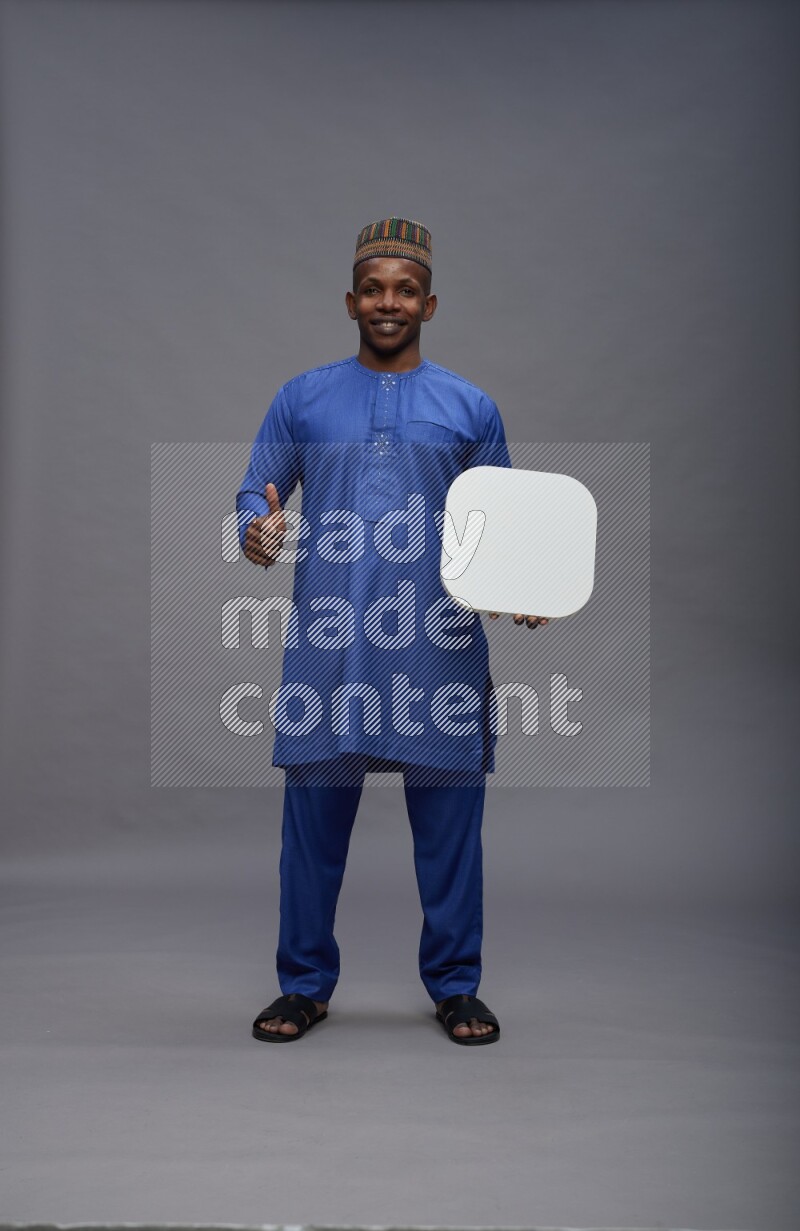 Man wearing Nigerian outfit standing holding social media sign on gray background