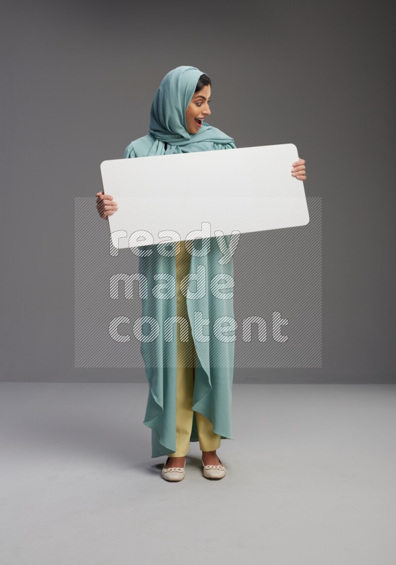 Saudi Woman wearing Abaya standing holding board on Gray background