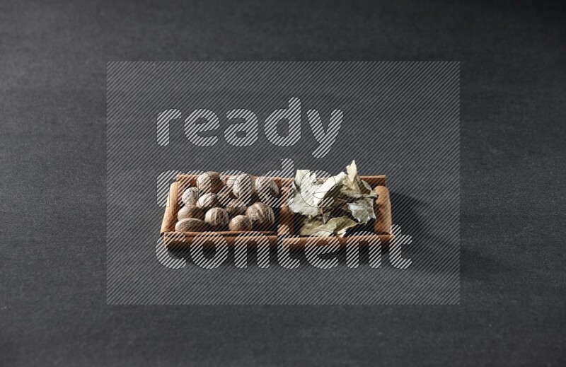 مربعان من أعواد القرفة ممتلئان بجوزة الطيب وأوراق الغار علي خلفية سوداء