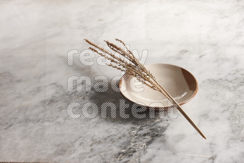 Wheat stalks on multicolored pottery plate on grey marble background