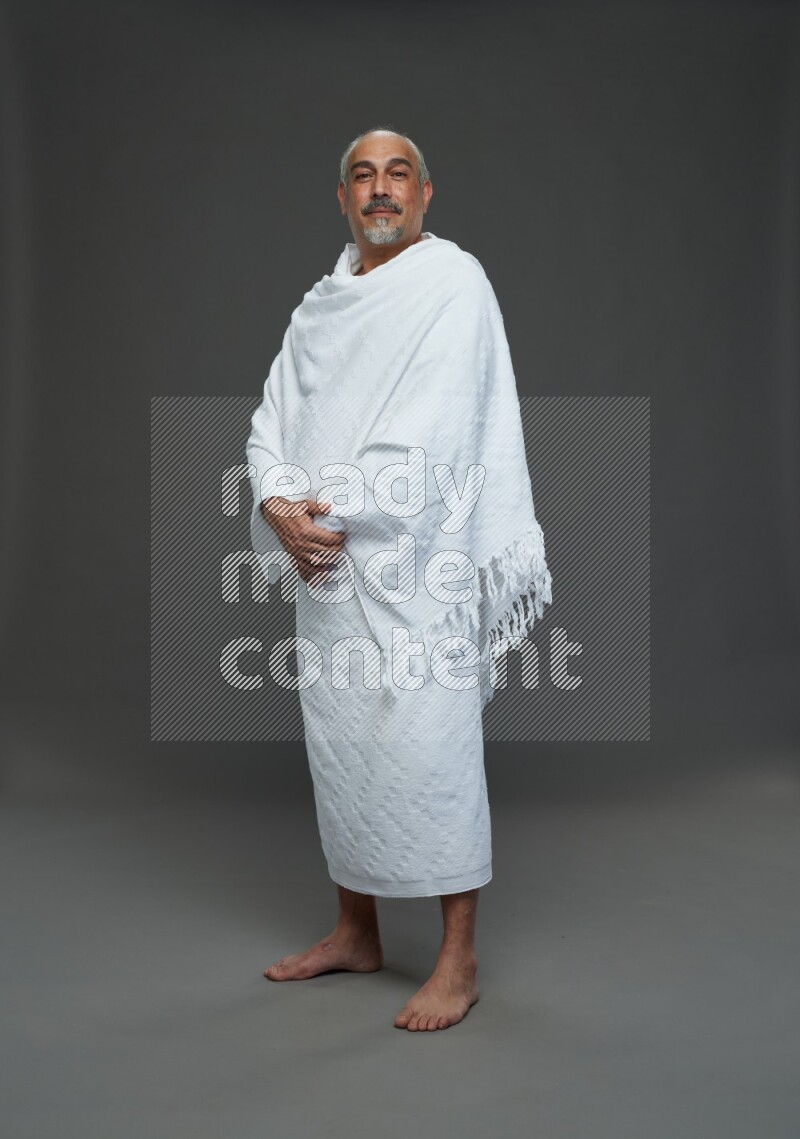 A man wearing Ehram Standing Interacting with the camera on gray background