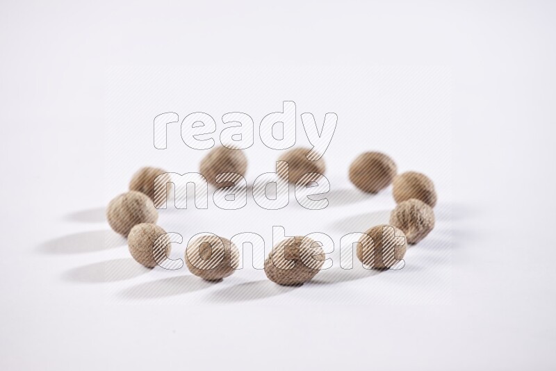 Nutmeg seeds in a circle shape on a white flooring