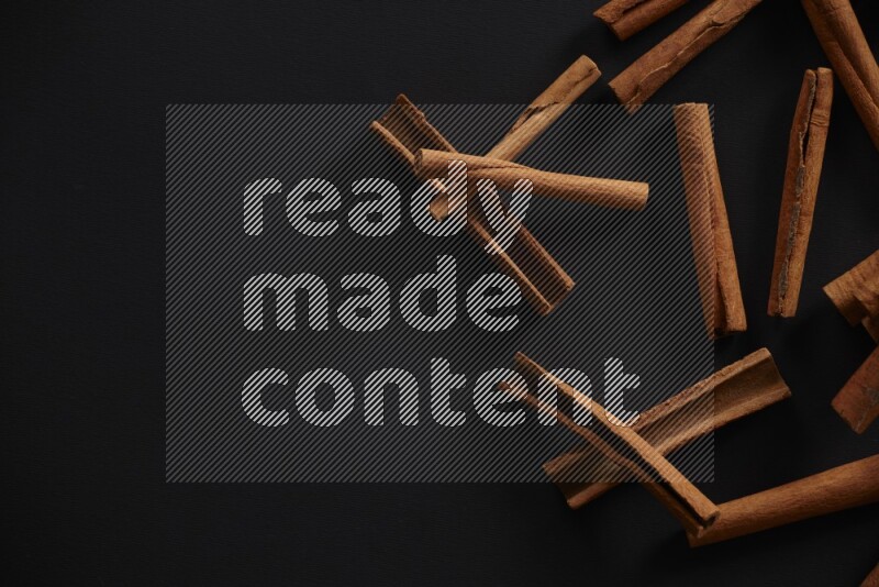 Cinnamon sticks stacked on black flooring