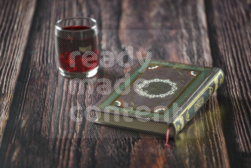 Quran with dates, prayer beads and different drinks all placed on wooden background