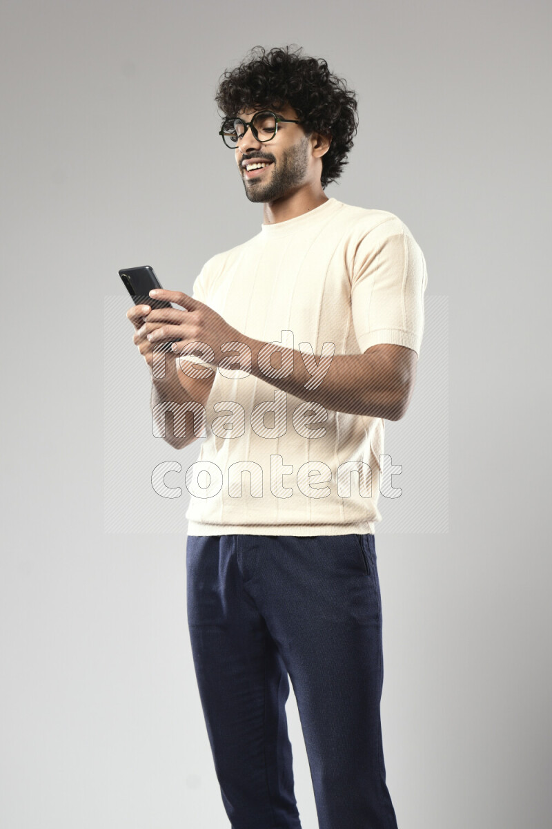 A man wearing casual standing and texting on the phone on white background