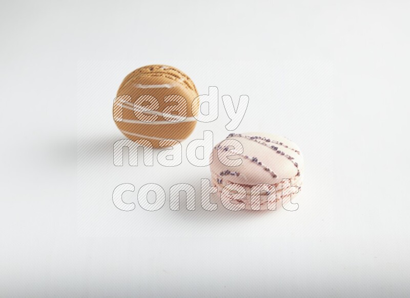 45º Shot of of two assorted Brown Irish Cream, and pink orange blossom macarons on white background
