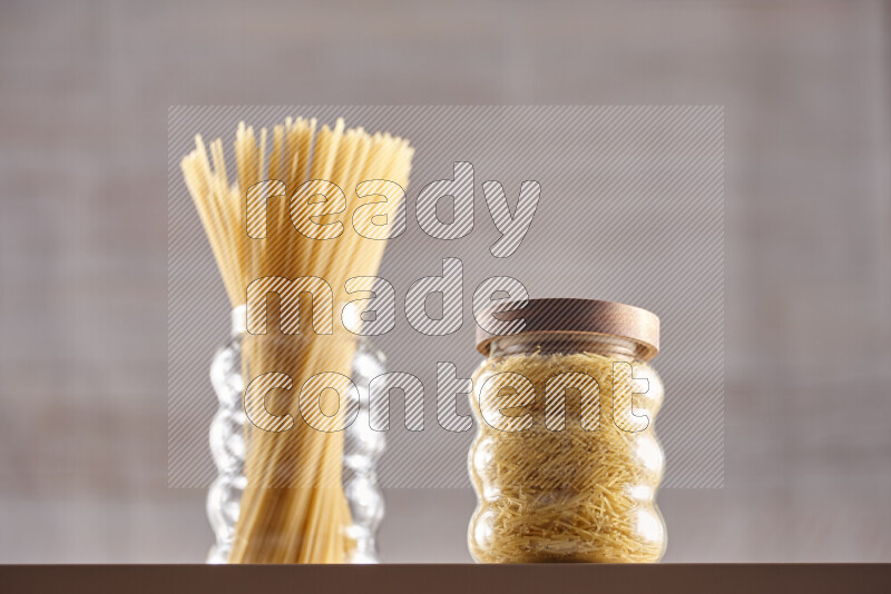 Raw pasta in glass jars on beige background