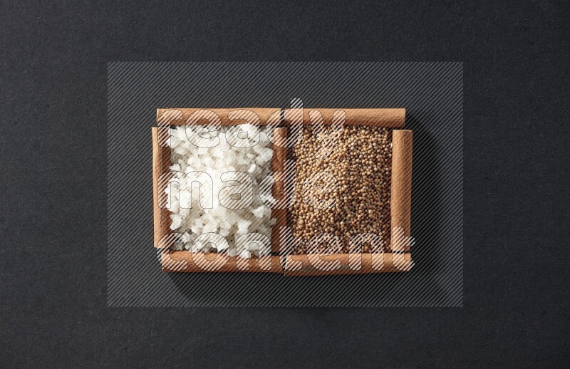 2 squares of cinnamon sticks full of mustard seeds and white salt on black flooring